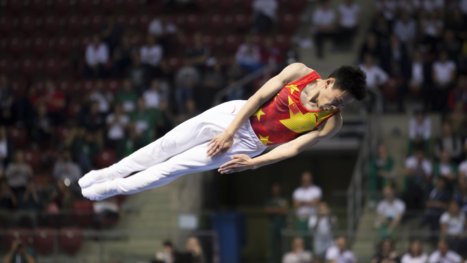 Photographie couleur du chinois Gao Lei, champion du monde de Trampoline, en train d'effectuer un salto en position tendu