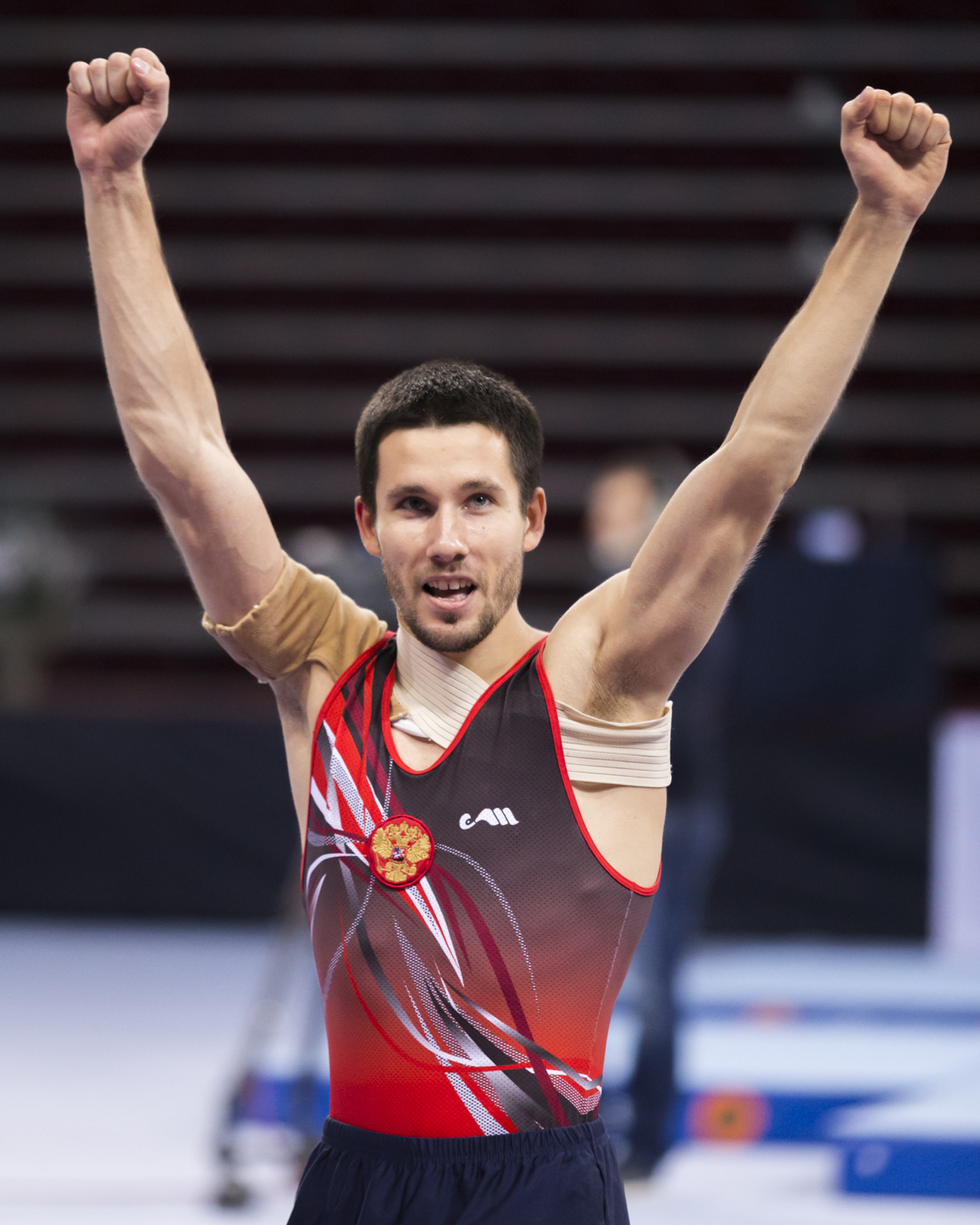 Photographie couleur de Mikhail Zalomin, champion du monde de double mini trampoline, qui lêve les bras de joie d'avoir réussi sa compétition