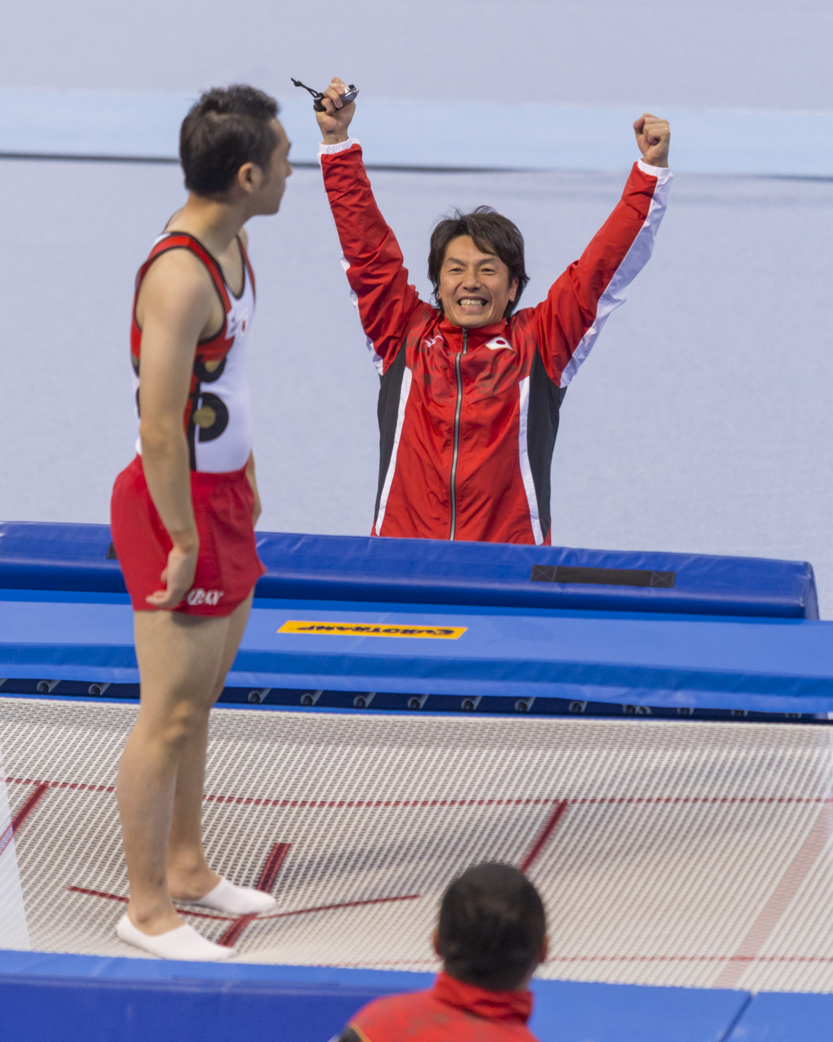 Photographie couleur du japonais Tetsuya Sotomura et de son entraineur montrant sa joie après le passage de Trampline de son gymnaste