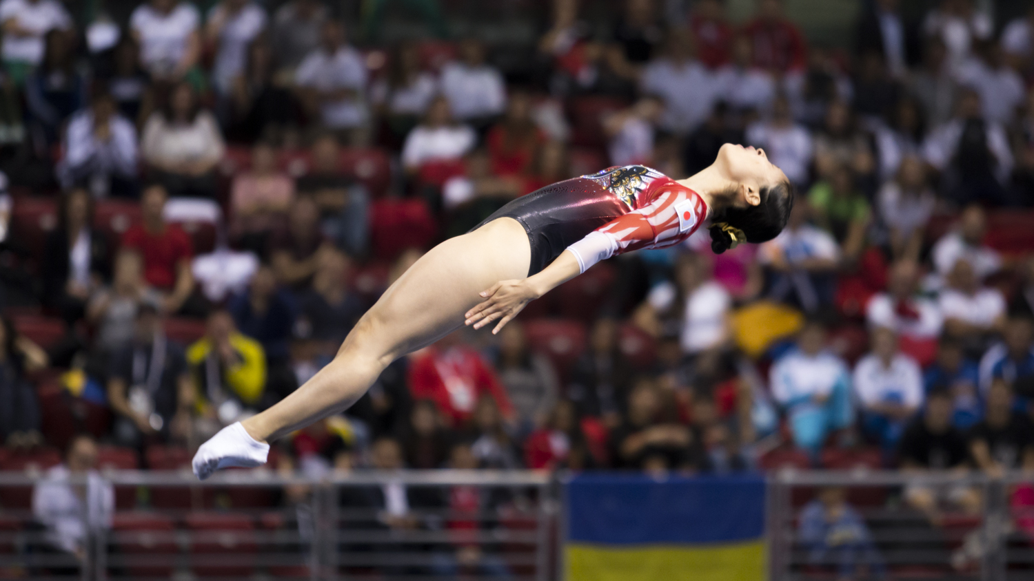 Photographie couleur d'une gymnaste Japonaise en Trampoline en position de salto arrière tendu
