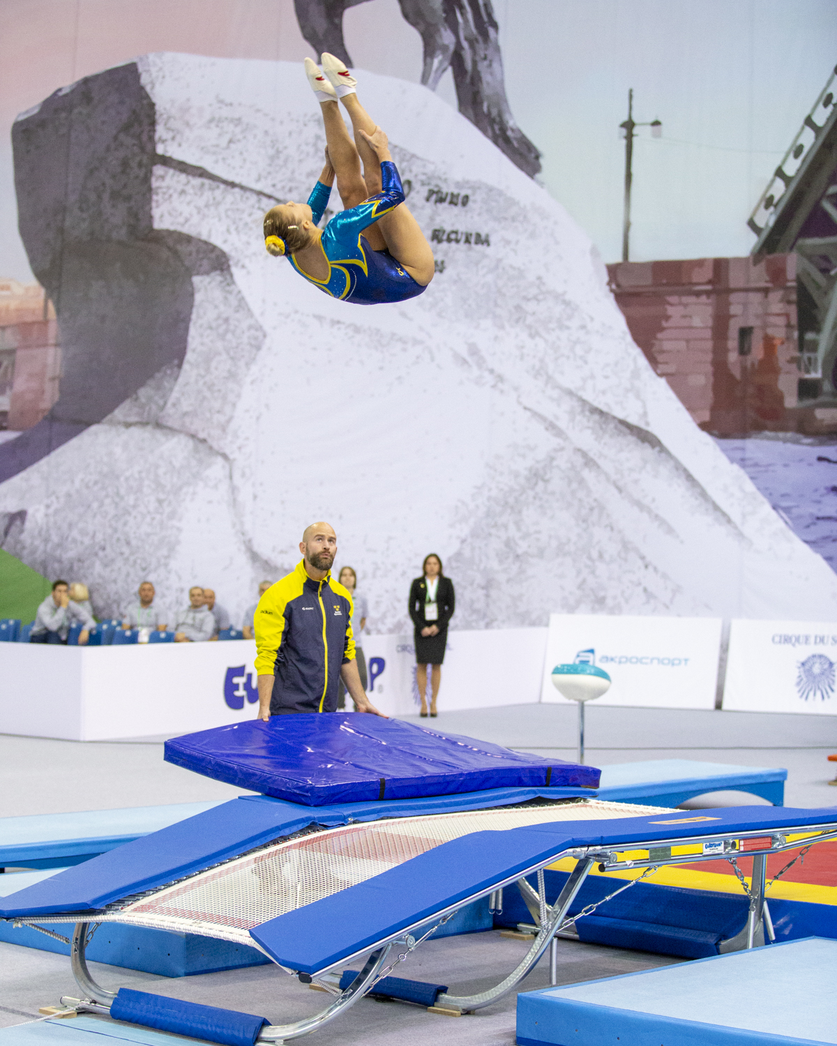 Photographie couleur de la suédoise Lina Sjoeberg, double championne du monde de double mini trampoline et position carpé sous le regard de son entraineur